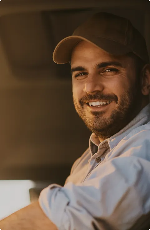Een glimlachende chauffeur achter het stuur van zijn vrachtwagen, elleboog op het portier