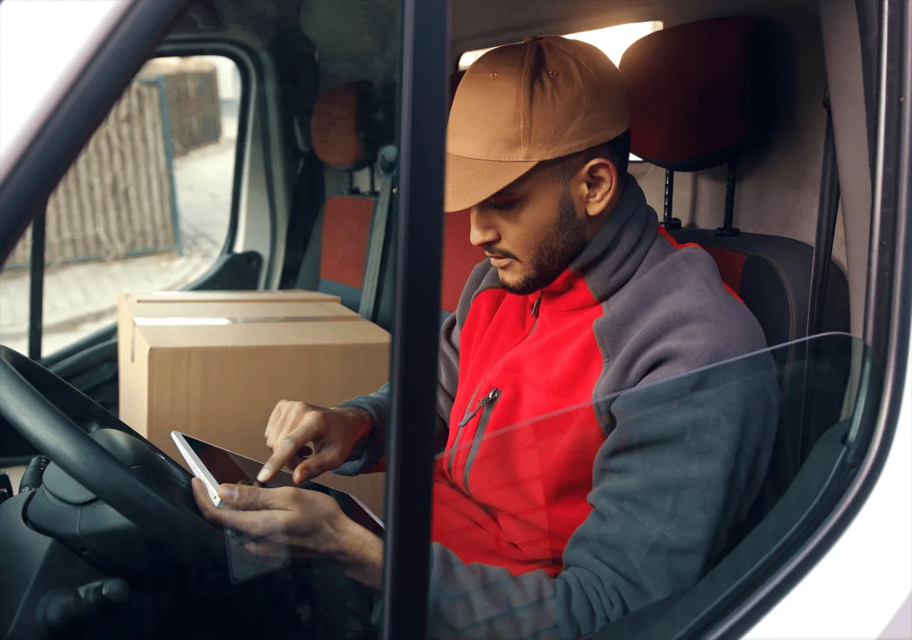 Een koerier achter het stuur van zijn bestelwagen, met zijn telefoon in de hand